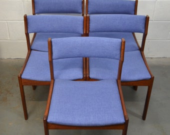 May include: A set of five mid-century modern chairs. Each chair has a light blue upholstered seat and backrest, with a wooden frame and legs. The chairs are arranged in a group, showcasing their design.