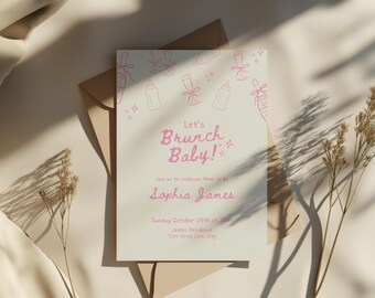 May include: A baby shower invitation with the text "Let's Brunch Baby!" in pink script. The invitation features illustrations of baby bottles and champagne flutes. The invitation is on a cream-colored card with a brown envelope.