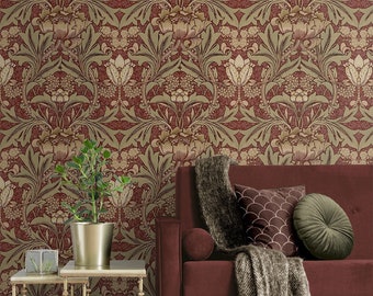 May include: A living room scene featuring a burgundy sofa with decorative pillows and a fringed throw. The background is a floral wallpaper in shades of red, gold, and green. A gold side table holds a potted plant and a glass box.
