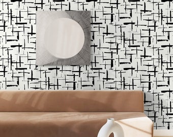 May include: A brown couch with a white coffee table and a white vase with a hole in the side. The wall behind the couch is covered in black and white abstract wallpaper.
