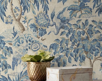 May include: A gold metal planter with a textured surface sits on a wooden table in front of a blue and white floral wallpaper. A white box with gold marbling is next to the planter.