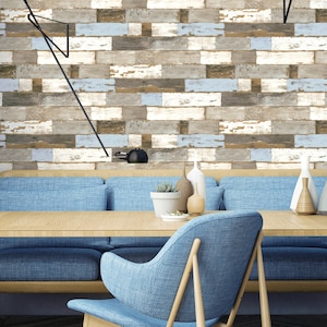 May include: A blue sofa and chair with wooden legs sit in front of a wall with a wood plank wallpaper design. The wall is decorated with two black lamps.