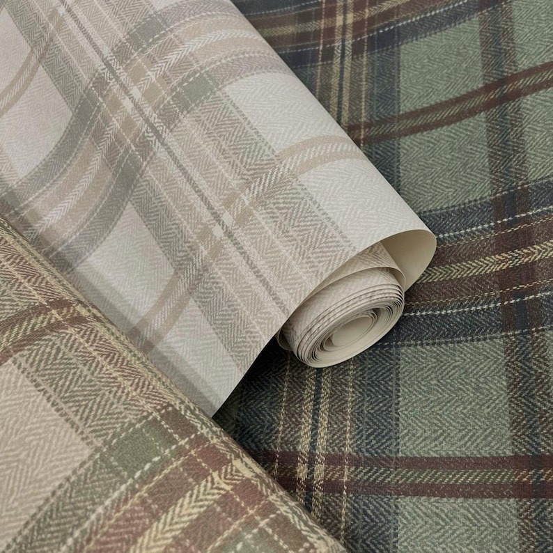 May include: Close-up of three rolls of wallpaper with plaid patterns. The rolls display a variety of colors, including beige, brown, and green. The patterns include classic plaid and herringbone designs, offering a textured and layered visual appeal.