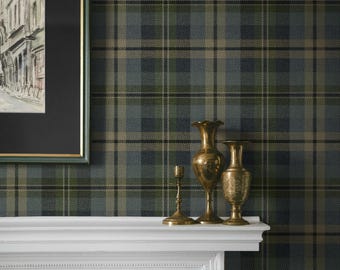 May include: A framed watercolor painting of a European street scene hangs above a white mantel. Three antique brass vases and a candlestick holder are arranged on the mantel. The background is a plaid wallpaper in shades of green, blue, and tan.