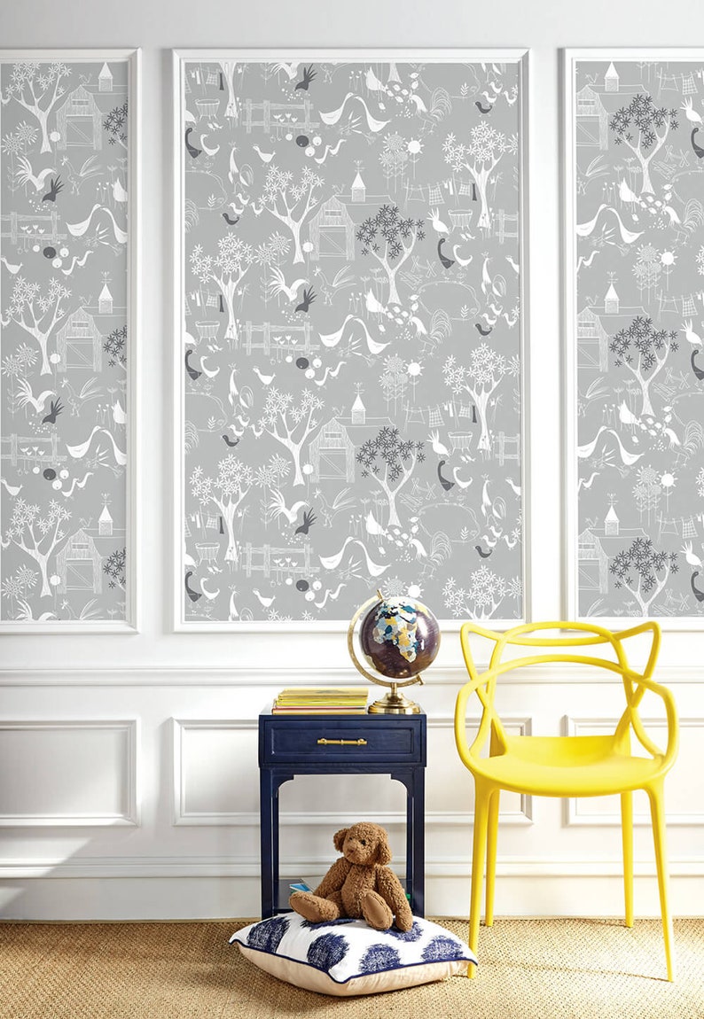 Puede incluir: Una silla amarilla con un dise&ntilde;o &uacute;nico se encuentra frente a una pared con un papel tapiz gris y blanco que presenta un patr&oacute;n repetitivo de p&aacute;jaros, &aacute;rboles y casas. Una mesita de noche azul con un oso de peluche y un globo terr&aacute;queo se encuentra junto a la silla.