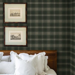 May include: A white bed with a wooden headboard and white pillows. The wall behind the bed is covered in green and white plaid wallpaper.