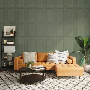 May include: A brown leather sectional sofa with a chaise lounge, two pillows, and a potted plant. The sofa is in front of a wall with a green patterned wallpaper. A black coffee table with a round top sits in front of the sofa.