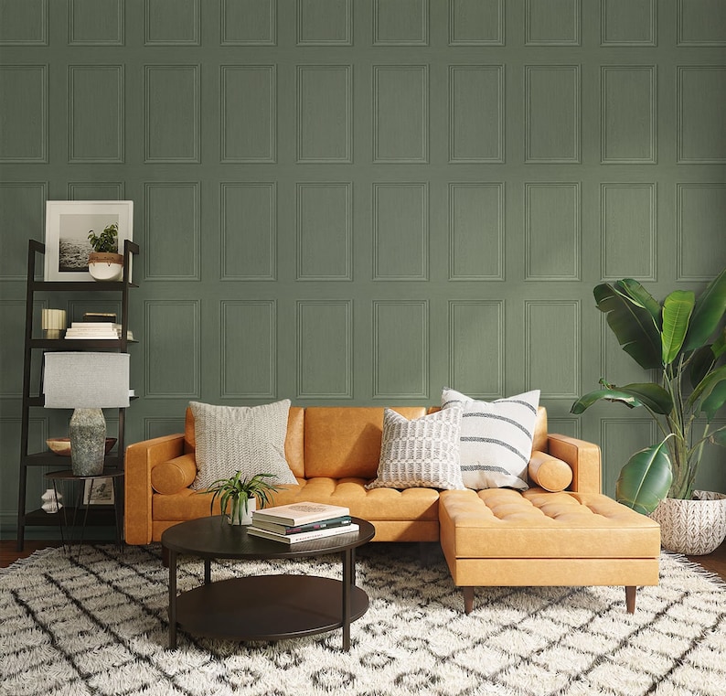 May include: A brown leather sectional sofa with a chaise lounge, two pillows, and a potted plant. The sofa is in front of a wall with a green patterned wallpaper. A black coffee table with a round top sits in front of the sofa.