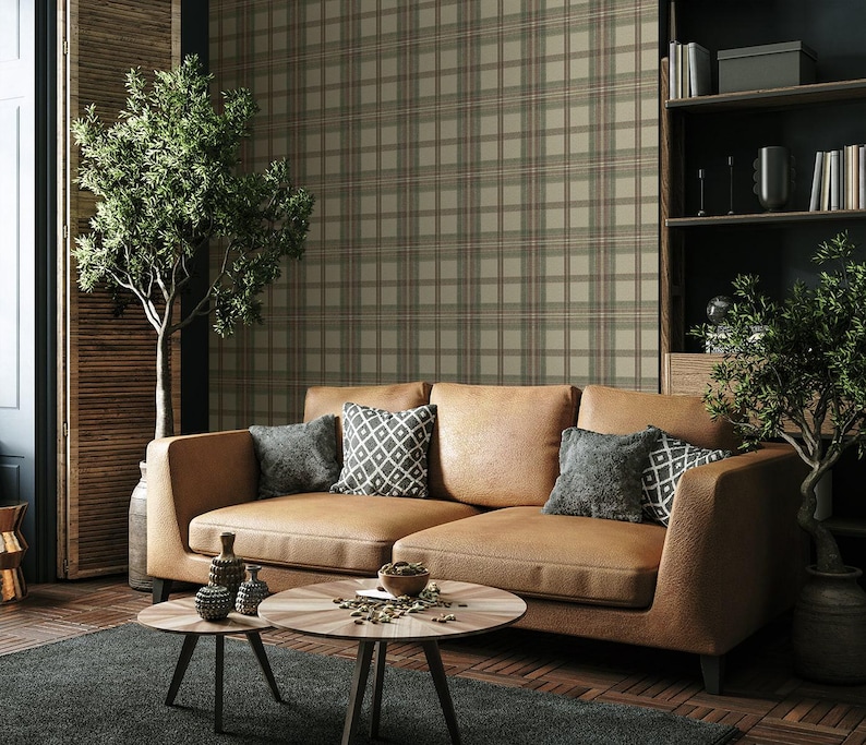 May include: A modern living room featuring a tan leather sectional sofa with decorative pillows. Two round wooden coffee tables sit on a dark gray rug. The background includes a plaid wallpaper and a small tree.