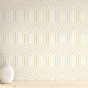 May include: A white wall with a geometric pattern wallpaper in gold. Two vases, one white and one brown, are placed on a wooden surface in front of the wall.