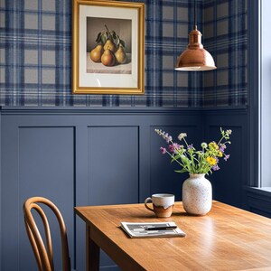 May include: A dining room scene featuring a wooden table, chair, and a vase of flowers. A framed picture of pears hangs on a plaid wallpapered wall. A copper pendant light hangs above the table.