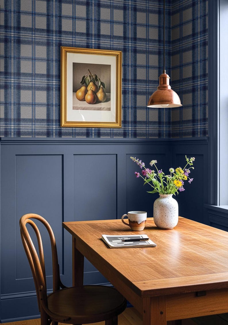 May include: A dining room scene featuring a wooden table, chair, and a vase of flowers. A framed picture of pears hangs on a plaid wallpapered wall. A copper pendant light hangs above the table.