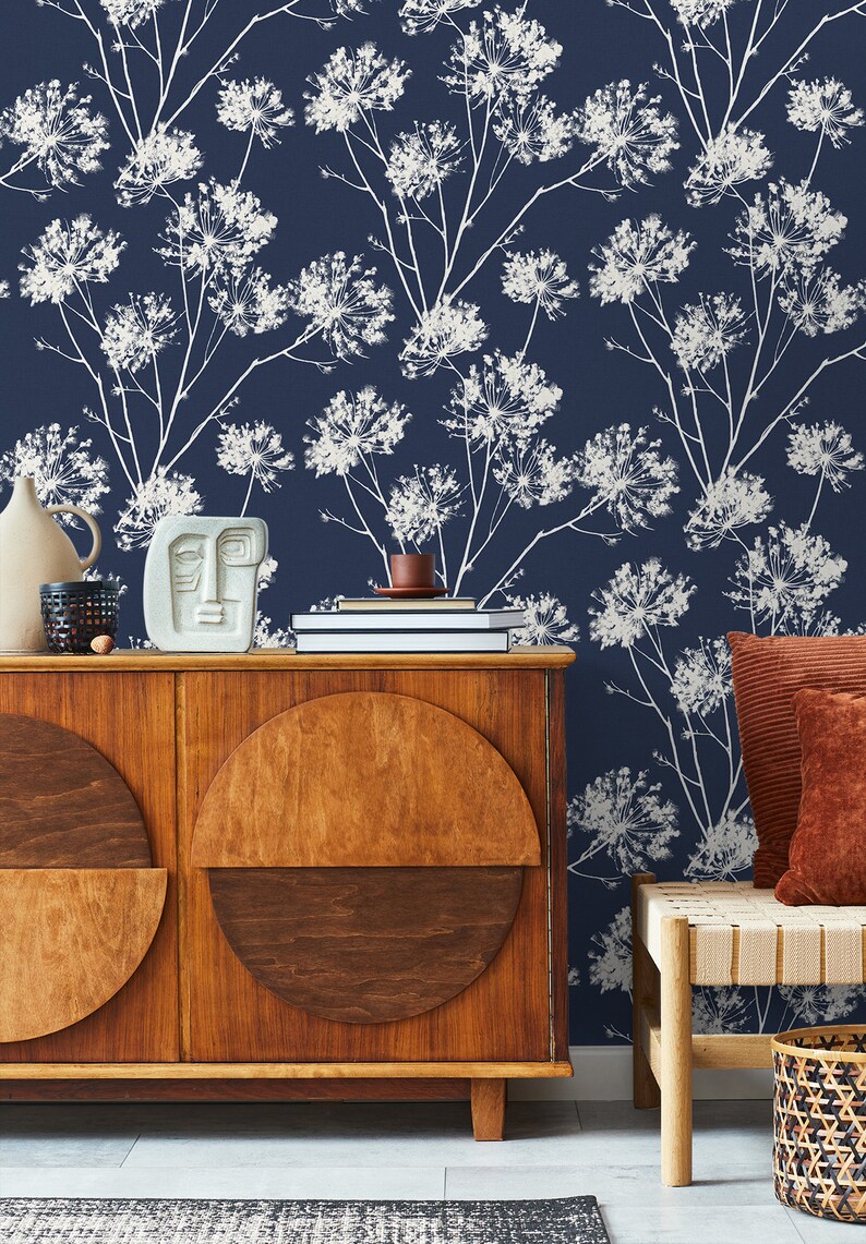 May include: A dark blue wallpaper with a white floral pattern. The wallpaper is in a living room with a wooden cabinet and a bench with a woven seat.