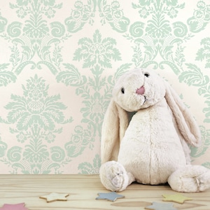 May include: A white plush bunny rabbit toy sitting on a wooden surface with a light green and white damask patterned wallpaper in the background.