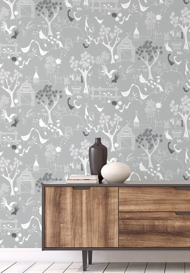 Puede incluir: Un papel tapiz gris y blanco con un patr&oacute;n repetitivo de p&aacute;jaros estilizados, &aacute;rboles y granjas. Una c&oacute;moda de madera con dos cajones se encuentra delante del papel tapiz. Un jarr&oacute;n negro y un cuenco de cer&aacute;mica blanco est&aacute;n encima de la c&oacute;moda.