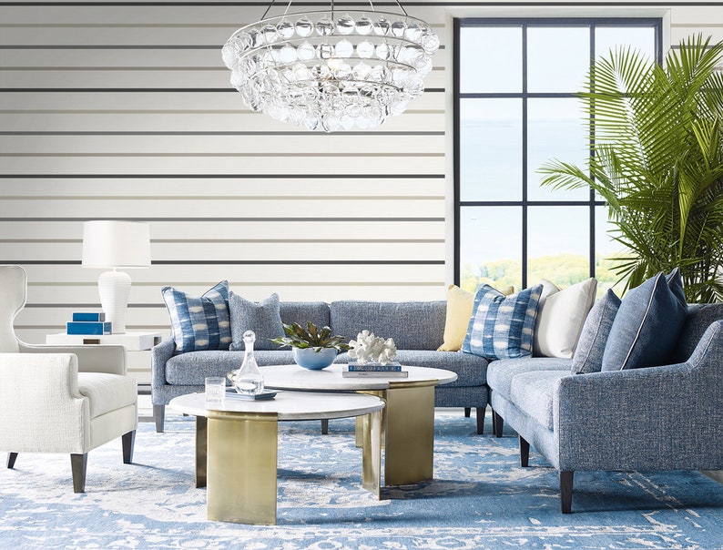 Puede incluir: Un sal&oacute;n moderno con un sof&aacute; seccional azul, sillones blancos y una alfombra azul estampada. Dos mesas de centro redondas de m&aacute;rmol blanco con bases doradas est&aacute;n frente al sof&aacute;. Una ventana grande y una l&aacute;mpara de ara&ntilde;a de cristal.