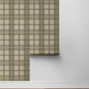 May include: A roll of wallpaper with a classic plaid pattern in shades of beige, brown, and green. The wallpaper is displayed against a white wall and a wooden floor, showcasing its design and texture.