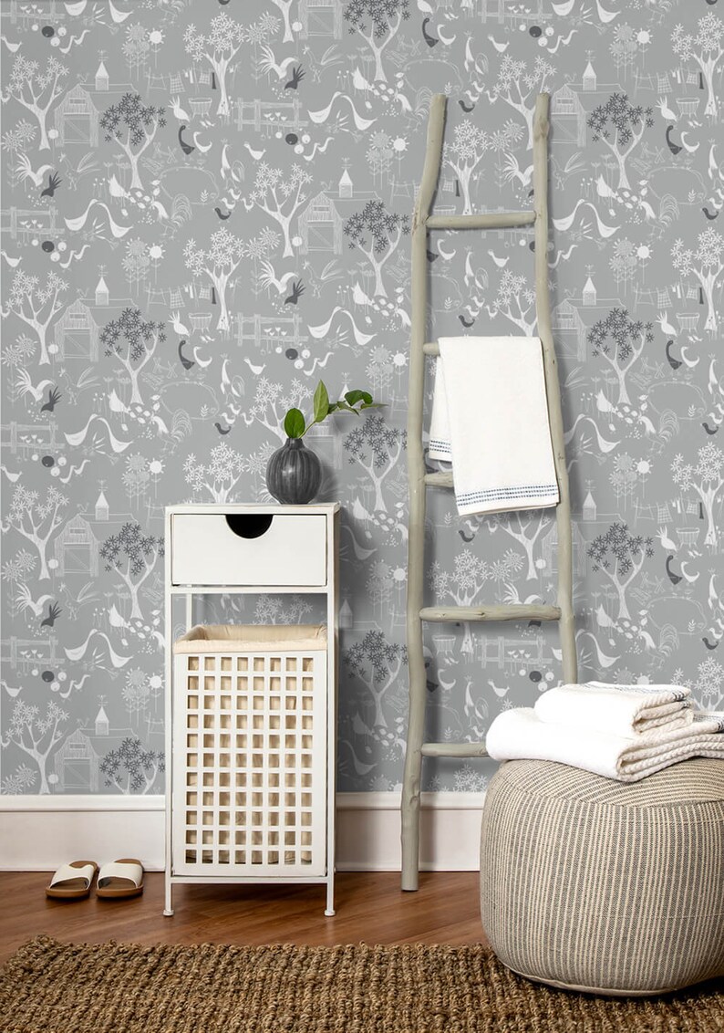 Puede incluir: Un papel tapiz con estampado gris y blanco con una unidad de almacenamiento blanca, una escalera de madera y una otomana a rayas. El papel tapiz presenta un patr&oacute;n repetitivo de &aacute;rboles estilizados, p&aacute;jaros y casas.