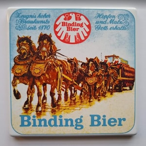 May include: Square Binding Bier coaster with a vintage design. The image features a team of horses pulling a beer wagon. The coaster has a light blue border and text that reads "Binding Bier".