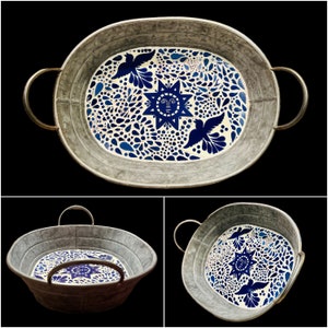 May include: A silver metal serving tray with a blue and white floral design. The design features a sun with a face and birds.