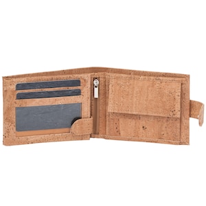 Puede incluir: Una cartera de corcho marr&oacute;n con un compartimento con cremallera y m&uacute;ltiples ranuras para tarjetas. La cartera est&aacute; abierta para revelar el interior.