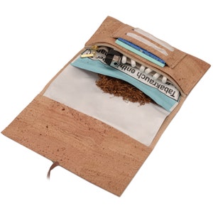 Könnte beinhalten: Eine braune Tabaktasche aus Korkleder mit Reißverschluss. Die Tasche ist geöffnet und enthält eine Packung Drehtabakpapier, ein Feuerzeug, eine Packung Zigarettenfilter und eine Tüte Tabak.