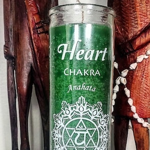 May include: A green candle with the words "Heart Chakra Anahata" in white script. A white mandala-style design is centered below the text. The words "Love & Connection I Love" are at the bottom. The candle is in a clear glass jar.
