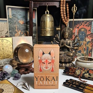 May include: A collection of spiritual items including a "YOKAI TAROT" deck, a crystal ball, a bronze bell, and a statue of a deity. The tarot box features a fox-like character. Other items include Japanese art prints, crystals, and a wooden arch.