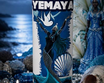 May include: A tall cylindrical glass candle featuring a white wax pillar and a label with the text YEMAYA. The label depicts a dark-skinned figure with long flowing hair, a white dove, and a large seashell against a blue ocean wave background.