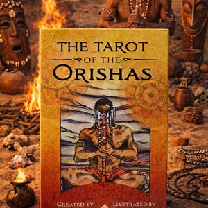 May include: A tarot card deck titled "The Tarot of the Orishas" with a colorful illustration of a person in a spiritual setting. The box features the text "Created by Zolrak" and "Illustrated by Durkon". The background includes fire and other spiritual objects.