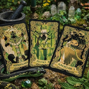 May include: Three tarot cards with gold and green illustrations and text, including "Hierophant," "Justice XI," and "Magician I." A green snake, crystals, and a lit candle are in the background. The cards have ornate borders.