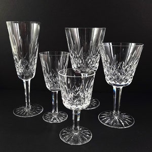 May include: Five clear glass drinking glasses of different sizes and shapes. The glasses are all made of cut crystal and have a decorative pattern.
