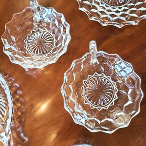 K&ouml;nnte beinhalten: Satz mit vier klaren Glasschalen mit einem Diamantenmuster und einem Sternendesign in der Mitte. Jede Schale hat einen Griff.