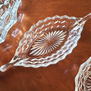 K&ouml;nnte beinhalten: Drei durchsichtige Glasschalen mit einem Diamantenmuster. Die Schalen befinden sich auf einer Holzoberfl&auml;che.