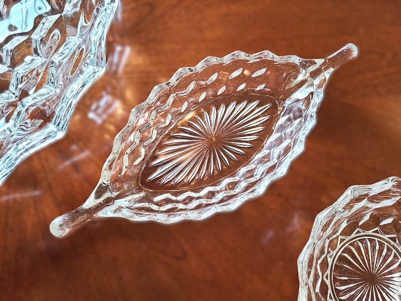 K&ouml;nnte beinhalten: Drei durchsichtige Glasschalen mit einem Diamantenmuster. Die Schalen befinden sich auf einer Holzoberfl&auml;che.