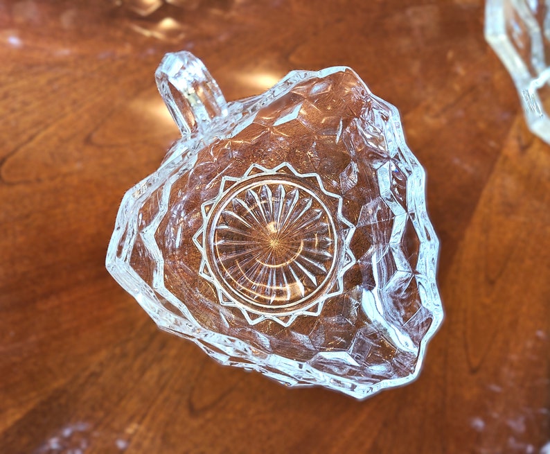 K&ouml;nnte beinhalten: Eine klare Glassch&uuml;ssel mit Diamantmuster und einem Griff. Die Sch&uuml;ssel hat ein dekoratives, kreisf&ouml;rmiges Design in der Mitte.