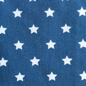 Könnte beinhalten: Nahaufnahme eines blauen Stoffes mit einem sich wiederholenden Muster aus weißen Sternen. Die Sterne sind gleichmäßig über die Oberfläche verteilt und erzeugen ein patriotisches oder himmlisches Design. Der Stoff hat ein leicht strukturiertes Aussehen.