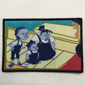 May include: Embroidered patch featuring a cartoon scene with three characters in blue overalls and a stern expression. The background has a light blue sky and a beige floor. The patch is bordered with black.