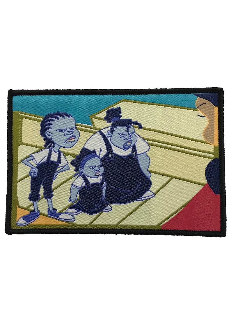 May include: Embroidered patch featuring three cartoon characters in blue overalls and white shirts, with stern expressions. The patch has a black border and a background of light blue and beige.