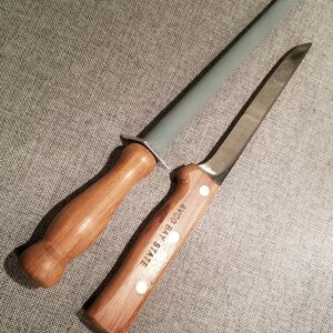May include: A wooden handled knife with a stainless steel blade and a wooden handled sharpening steel. The knife handle has the text "AYCO BAY STATE" engraved on it.