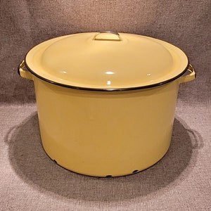May include: A large, yellow enamel pot with a lid and two handles. The pot has a black rim around the top and a black band around the bottom.