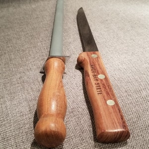 May include: A wooden handled knife with a steel blade and a wooden handled sharpening steel. The knife handle has the text "W.R. CASE & SONS" engraved on it.
