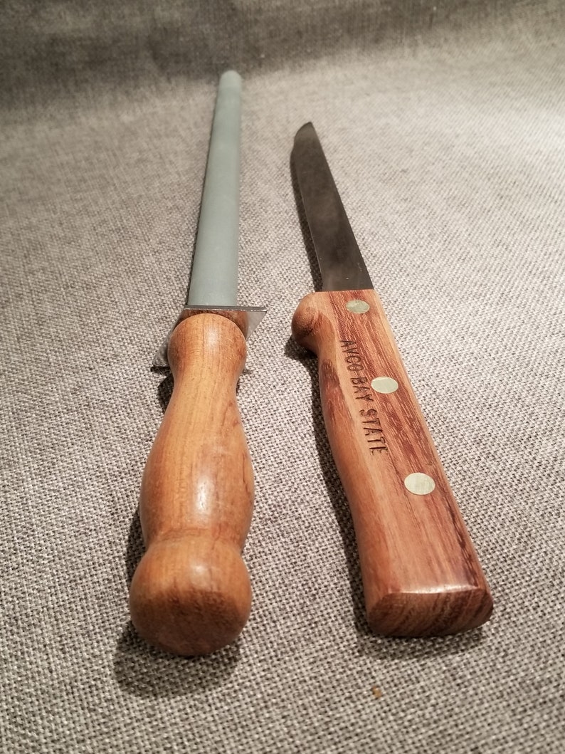 May include: A wooden handled knife with a steel blade and a wooden handled sharpening steel. The knife handle has the text "W.R. CASE & SONS" engraved on it.