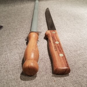May include: A wooden handled sharpening steel and a wooden handled knife with the text "W&uuml;sthof  Trident" on the handle.