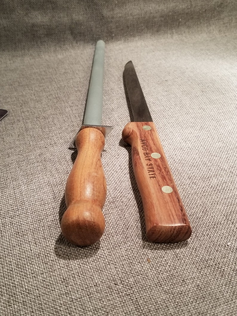 May include: A wooden handled sharpening steel and a wooden handled knife with the text "W&uuml;sthof  Trident" on the handle.
