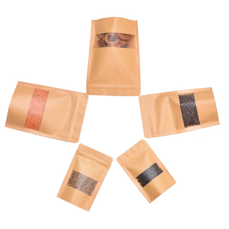 May include: Five brown paper bags with clear plastic windows, each containing different types of dried food products. The bags have a zipper closure.
