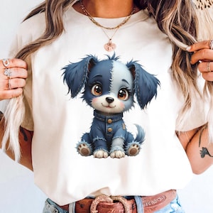 以下が含まれることがあります： クリーム色のTシャツ。青と白の毛並みでデニムジャケットを着た漫画の子犬のイラスト。子犬は大きな茶色の目をしています。この画像は、子供服やアクセサリーに適したデジタルイラストです。