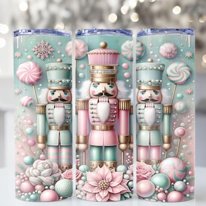 May include: A tumbler featuring a whimsical design with pastel colors. The design includes a nutcracker soldier in pink and teal, surrounded by candies, ornaments, and flowers. The tumbler is cylindrical and has a lid.