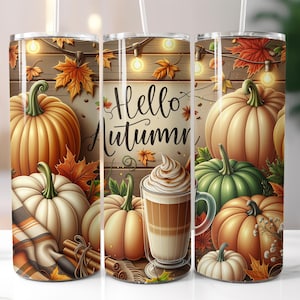 May include: A set of three stainless steel tumblers with a fall theme. Each tumbler features a design of pumpkins, autumn leaves, and the words "Hello Autumn". One tumbler shows a latte with whipped cream. The tumblers have white straws.