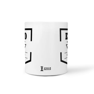 May include: White ceramic mug with a black graphic design featuring a square with a triangle inside and the text "Embrace the Suck". The mug has a black logo on the bottom that says "Stoic Design".